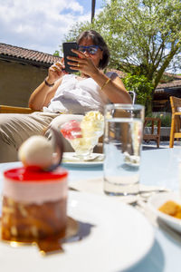 Low section of senior woman using phone siting on chair outdoors