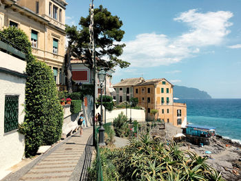 Buildings by sea against sky