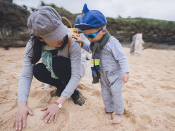 Mother and her baby boy playing sand on a beach