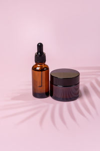 Set of skin care products on amber glass blank package on pink background. face and body treatment
