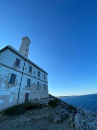 Building by sea against clear blue sky