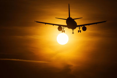 Low angle view of silhouette airplane against sky during sunset