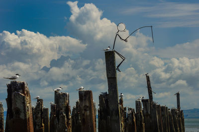 Low angle view of wooden posts in sea against sky