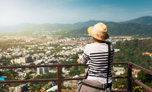 Rear view of man looking at cityscape against sky