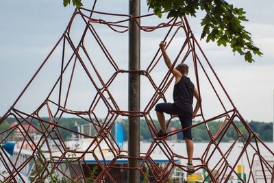 Full length of boy climbing rope in park