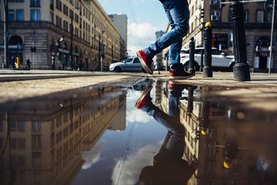 Reflection of man in puddle on street