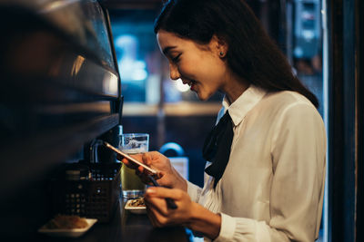 Side view of a young woman holding drink