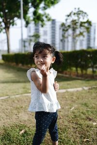 Portrait of cute girl on field at city garden 