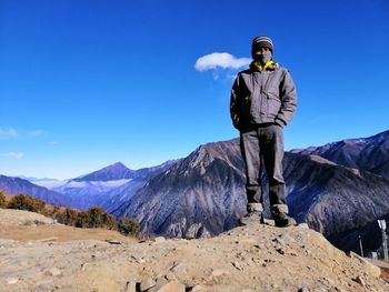 Portrait of man standing on mountain against blue sky