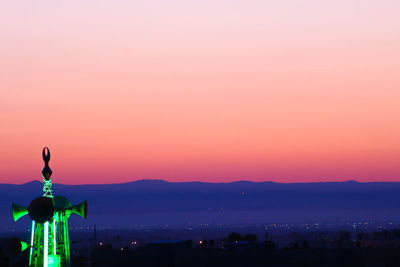 Illuminated cityscape against sky during sunset