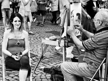 Artist painting woman sitting on chair at town square