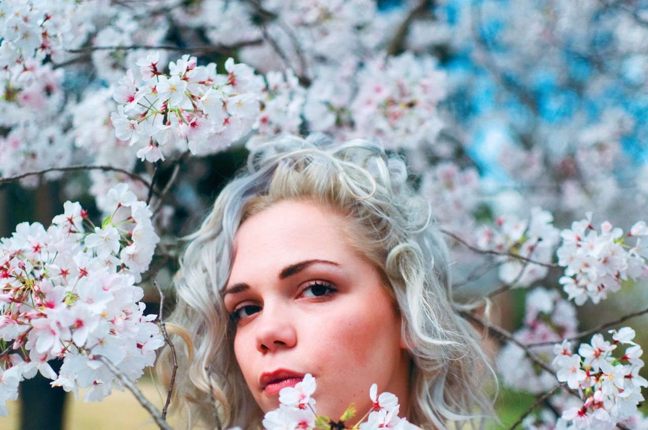 flower, flowering plant, plant, portrait, young adult, headshot, freshness, one person, young women, fragility, blond hair, beauty in nature, hair, nature, vulnerability, tree, women, beautiful woman, lifestyles, springtime, flower head, hairstyle, outdoors, cherry blossom