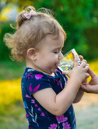 Side view of girl drinking water at park