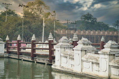 Bridge over river by buildings in city against sky