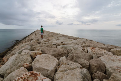 Rear view of man standing on jetty over sea against sky