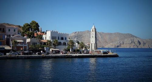 Buildings by sea against blue sky