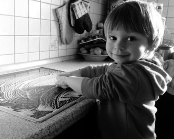 Portrait of cute boy cleaning tray in kitchen at home