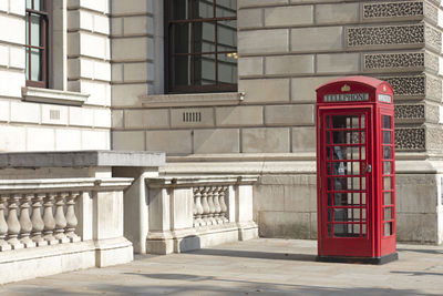 Red telephone booth on footpath in city