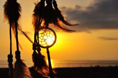 Close-up of silhouette dreamcatcher against sky during sunset