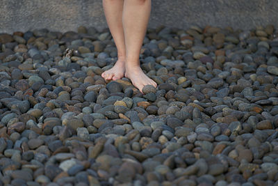 Low section of woman walk on pebbles stone