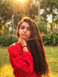 Portrait of beautiful young woman against trees