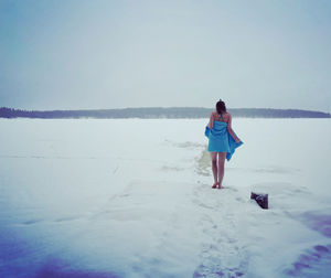 Rear view of woman standing on frozen lake 