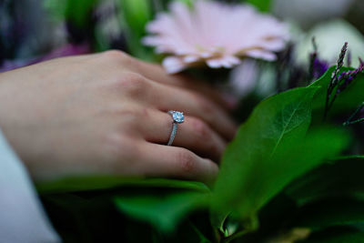 Close-up of hand with engagement ring holding flower