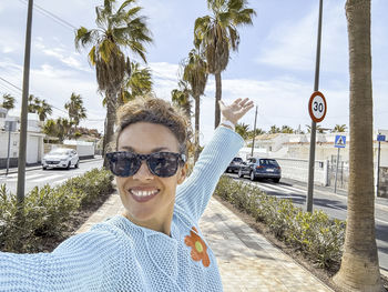 Portrait of woman wearing sunglasses while standing against sky
