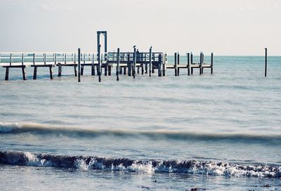 Pier over calm sea against clear sky