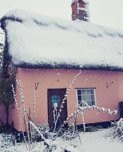 Snow covered house by building