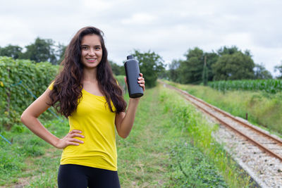 Young woman exercising on field against sky