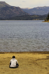 Rear view of man standing on sea shore against sky