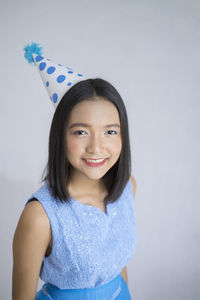 Portrait of a smiling young woman against wall