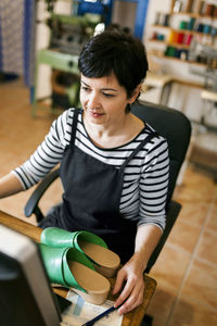 Shoemaker using computer in her workshop