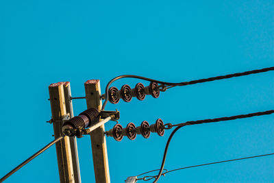 Low angle view of telephone pole against blue sky