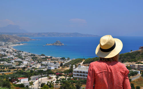 Rear view of woman looking at sea against cityscape