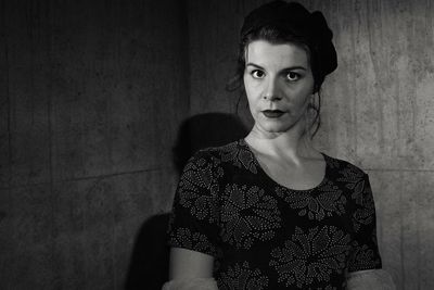 Portrait of a young woman against wall