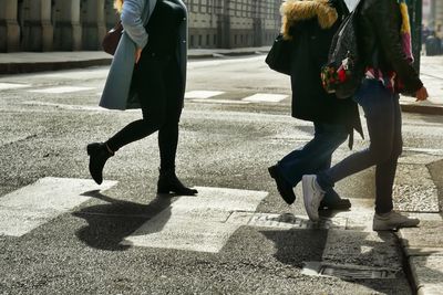 Low section of people walking on street in city