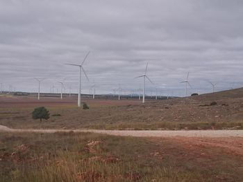 Windmills on field against sky