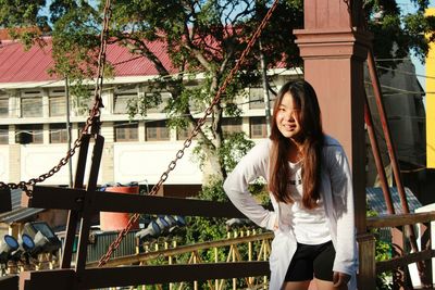 Smiling young woman standing against tree
