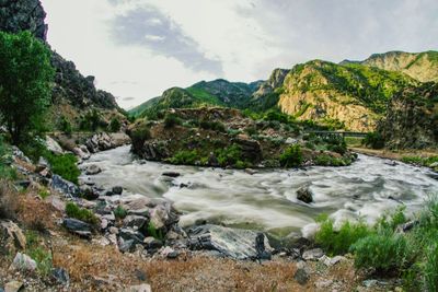 Scenic view of river amidst mountains against sky