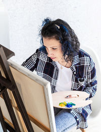 Woman looking at camera while sitting in mirror