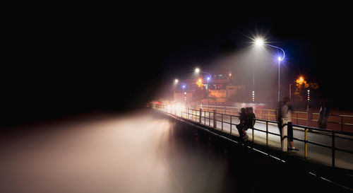 People on bridge at night during foggy weather