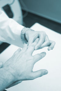 Cropped hand of doctor holding patient injured finger at hospital