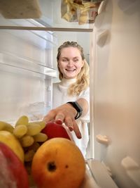 Portrait of young woman holding fruits at home