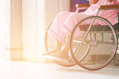 Low section of senior woman sitting on wheelchair at hospital