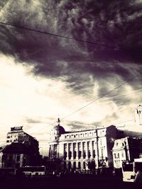 Cars on city street against cloudy sky
