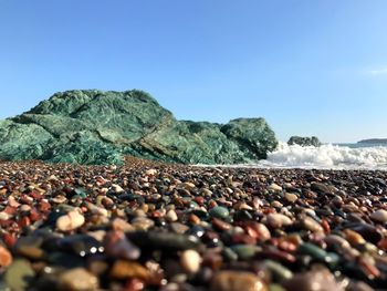 Surface level of stones on beach against clear sky