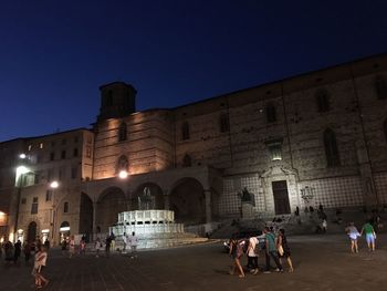 People at illuminated temple against clear sky at night