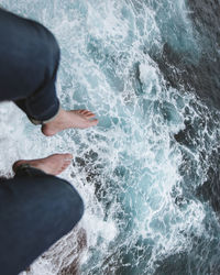 Low section of person sitting over flowing water